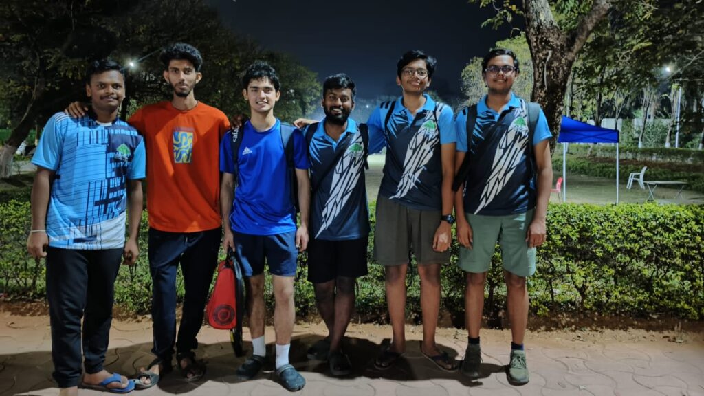 A picture of 6 people looking towards the camera, with their arms on others shoulders.