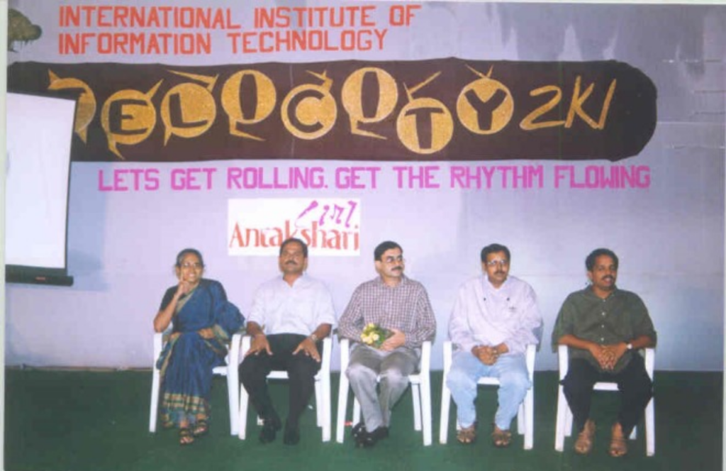 Five people are seated on plastic chairs in the centre of the image. Behind them reads: "International Insitute of / Information Technology", "Felicity 2k1", "Lets get rolling. Get the rhythm flowing" "Antakshari", all one below the other.