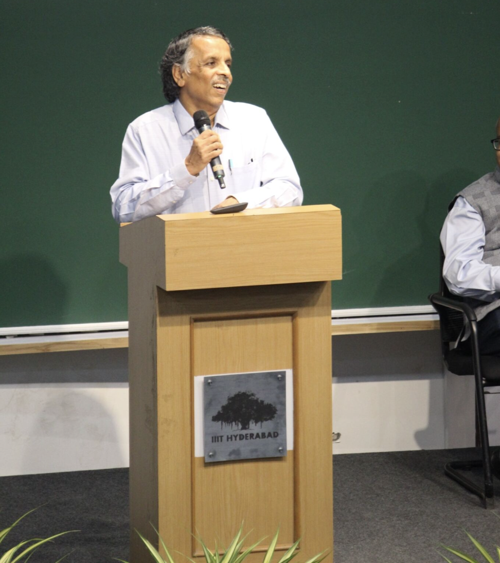 A picture of Prof. PJ Naraynan standing by a lectern, giving his last speech as a Director
